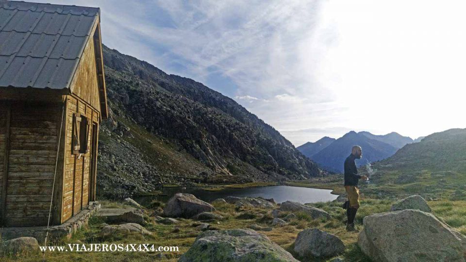 Refugio de montaña con un hombre observando la montaña