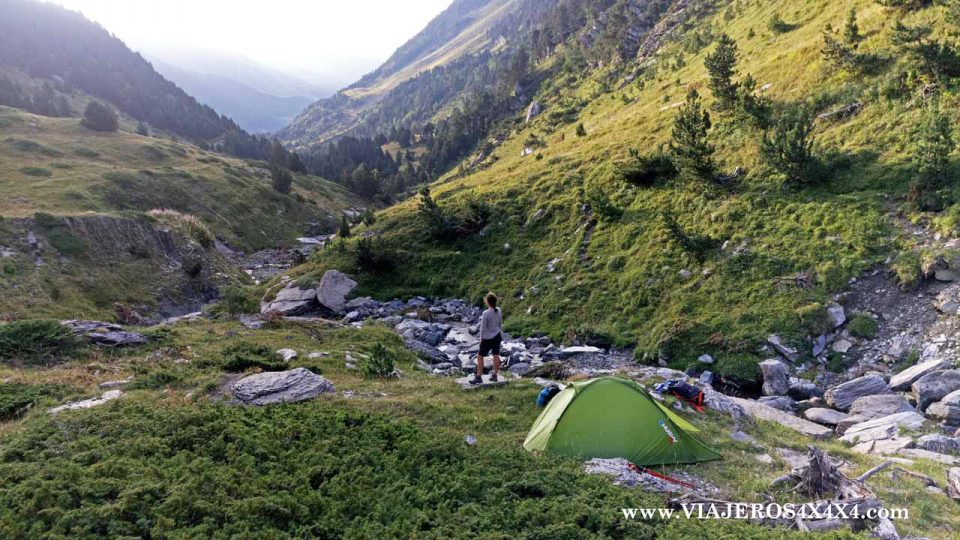 Tienda de acampada junto a un arroyo en medio de la montaña